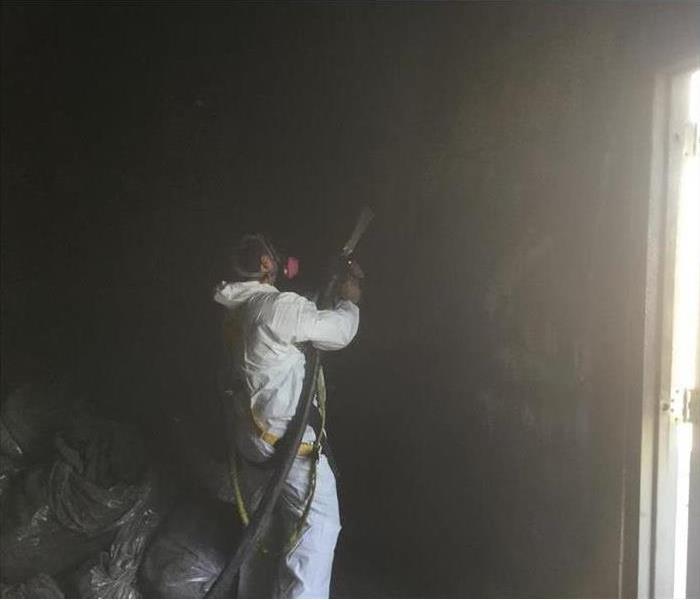 Restoration technician cleaning air area of a building damaged by smoke