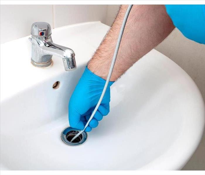 Plumbing issues, occupation in sanitation and handyman contractor concept with plumber repairing drain with plumbers snake